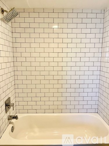 A white bathtub with a shower head above it.