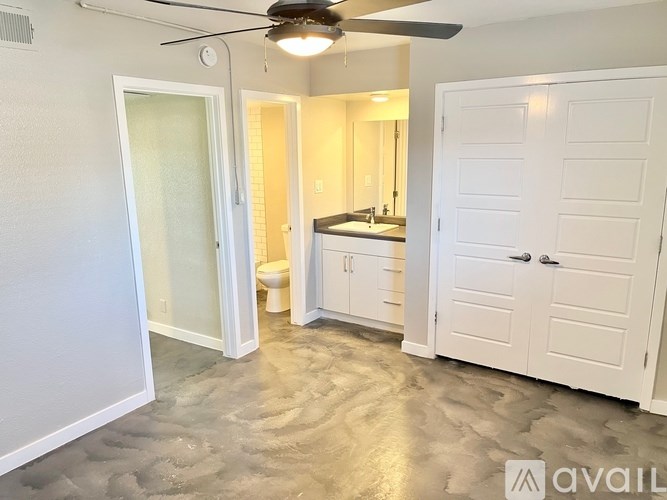 A room with a ceiling fan and a bathroom with a toilet and sink.
