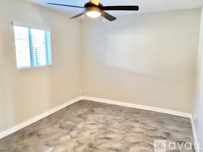 A room with a ceiling fan and a window with blinds.