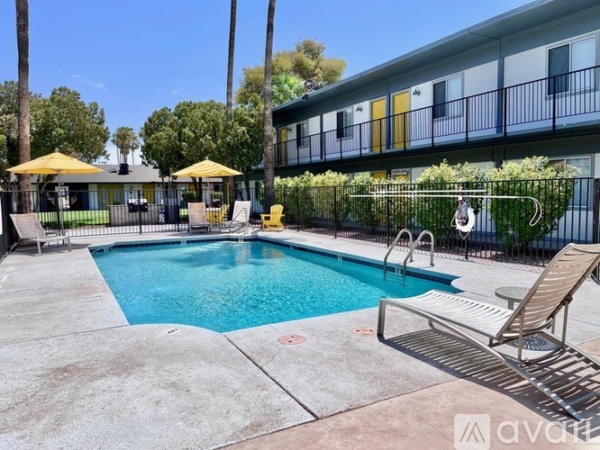 A pool area with a yellow umbrella and a metal fence.