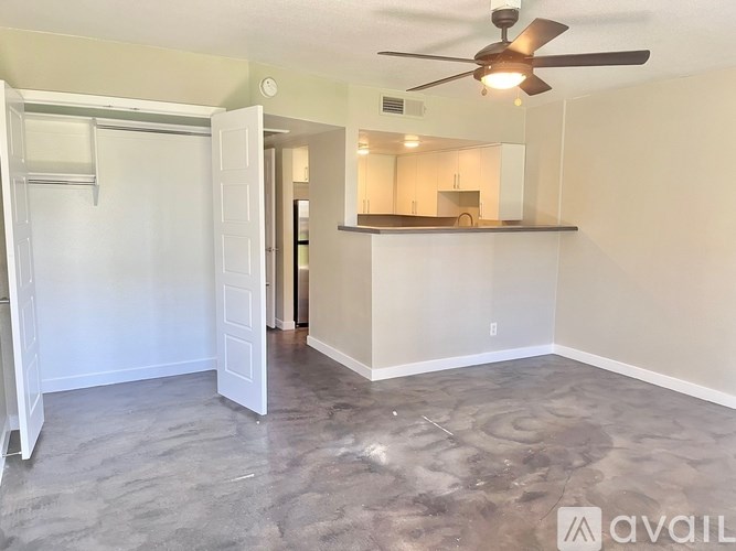 A room with a ceiling fan and a kitchenette area.