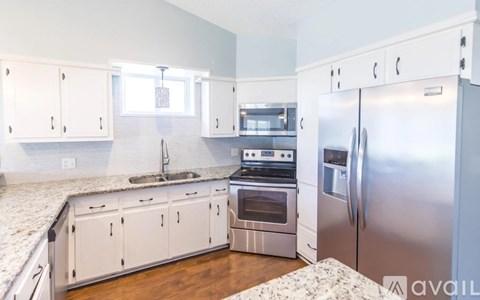 A kitchen with white cabinets and a granite counter top.