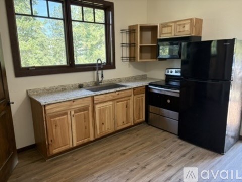 A kitchen with wooden cabinets and a black refrigerator.