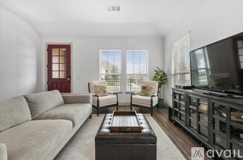 A living room with a brown leather coffee table and a grey sofa.
