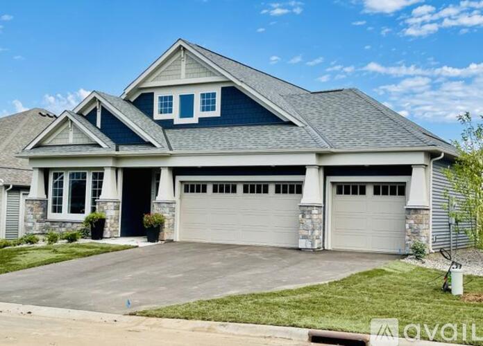 A two-car garage is attached to a house with a stone foundation.