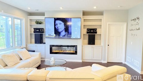 A living room with a white couch and a flat screen TV mounted on the wall.