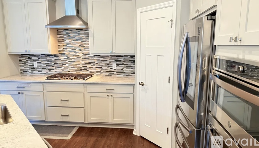 A kitchen with white cabinets and a stone backsplash.