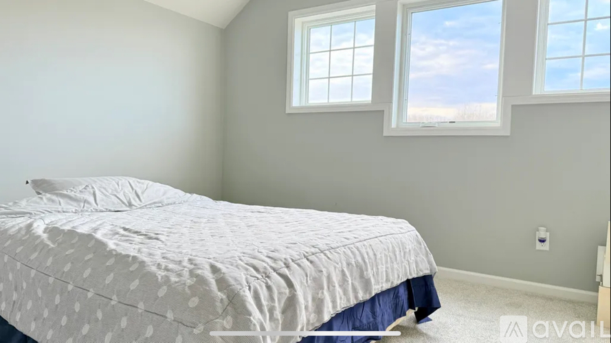 A bedroom with a bed, blue bed skirt, and a window.