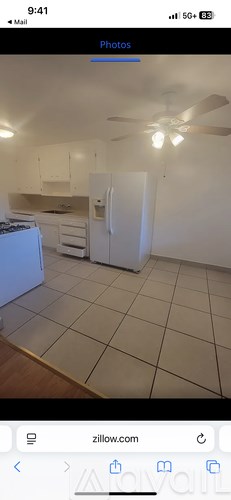 A white kitchen with a refrigerator and a ceiling fan.