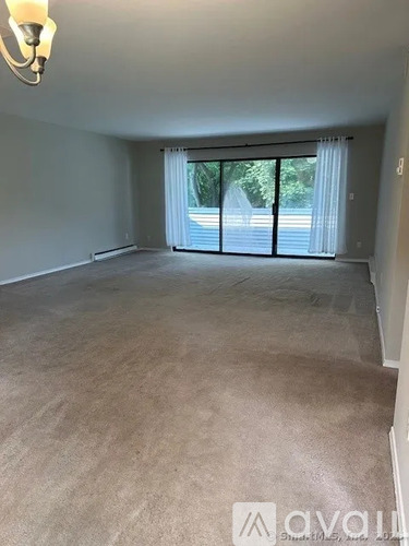 A room with a carpeted floor and a window with curtains.