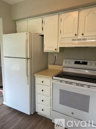 A white refrigerator is in a kitchen with white cabinets.