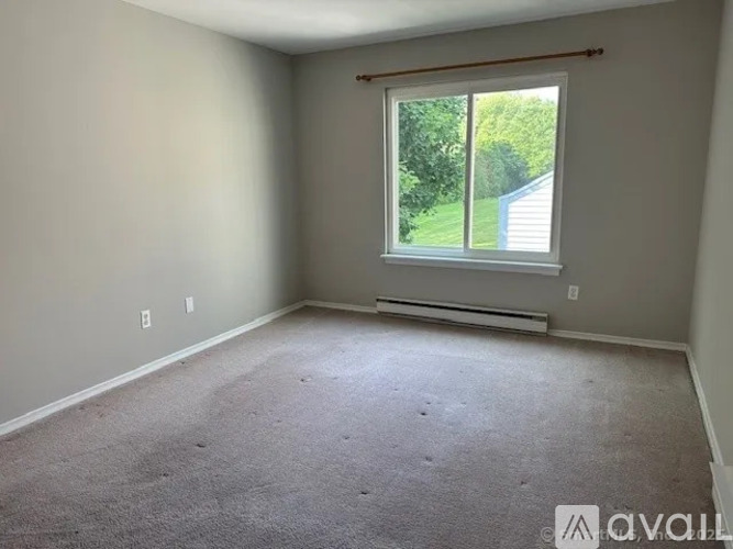 A room with a window and a carpeted floor.