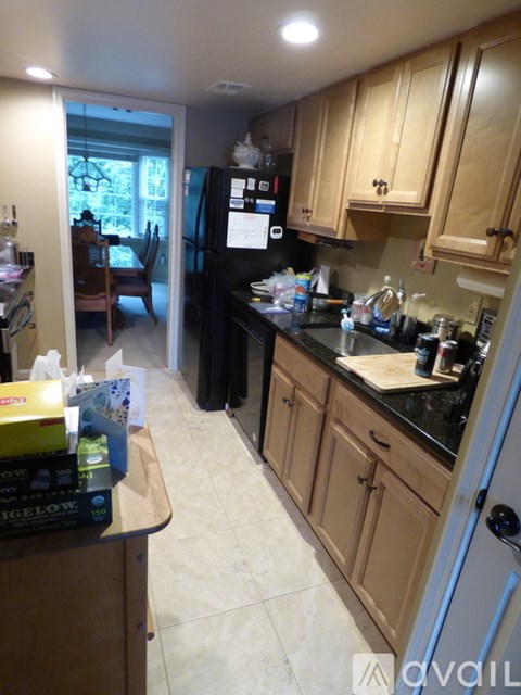 A kitchen with wooden cabinets and a black fridge.