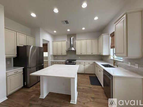 A kitchen with a table in the middle and a refrigerator on the left.