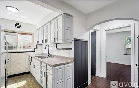 A kitchen with white cabinets and a black counter.