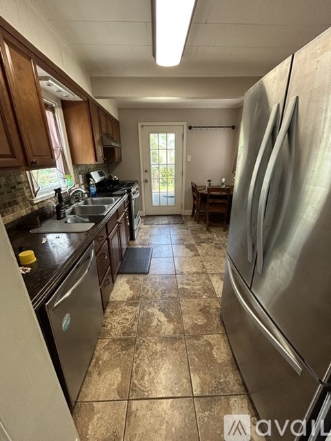 A kitchen with a tile floor and a refrigerator.