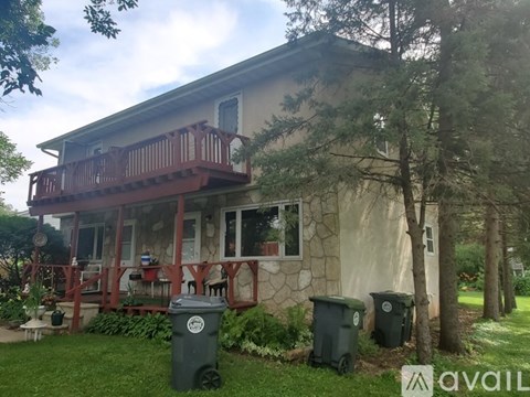 A house with a balcony and two trash bins in front.