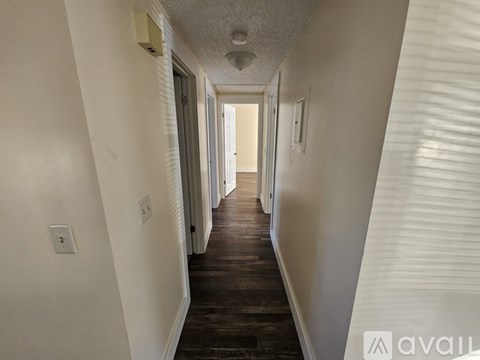 A long hallway with white walls and wood flooring.