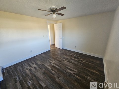 A room with a ceiling fan and wooden flooring.