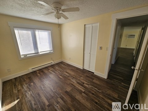 A room with a ceiling fan and wooden flooring.