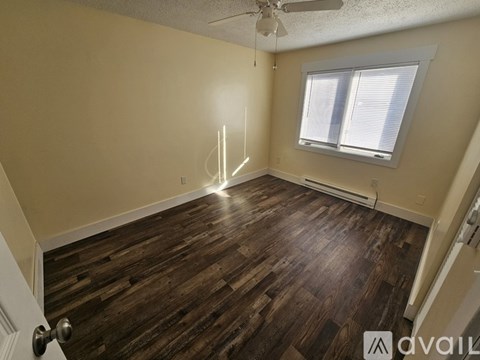 A room with wooden flooring and a window with blinds.