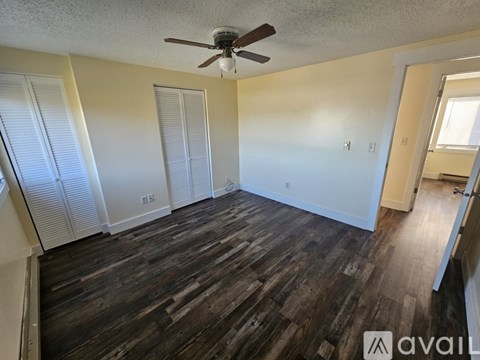 A room with a ceiling fan and wooden flooring.