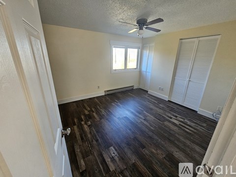 A room with a ceiling fan and wooden flooring.
