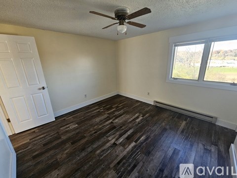 A room with a ceiling fan and wooden flooring.