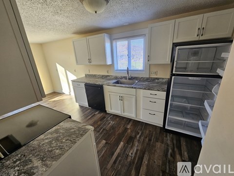 A kitchen with white cabinets and a granite countertop.