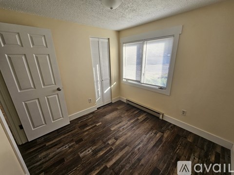 A room with a wooden floor and a window with blinds.