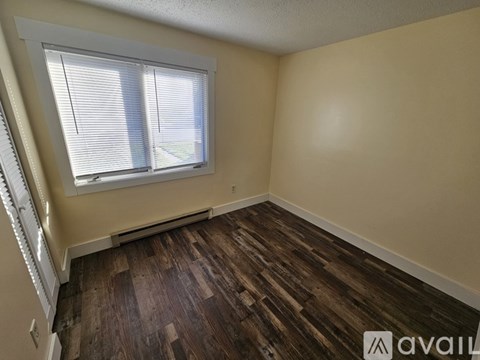 A room with wooden flooring and a window with blinds.