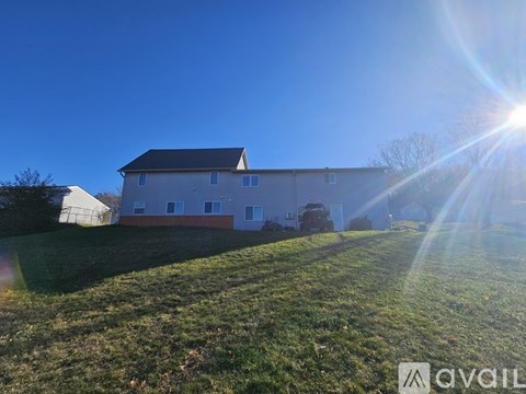 A house with a large lawn in front of it is bathed in sunlight.