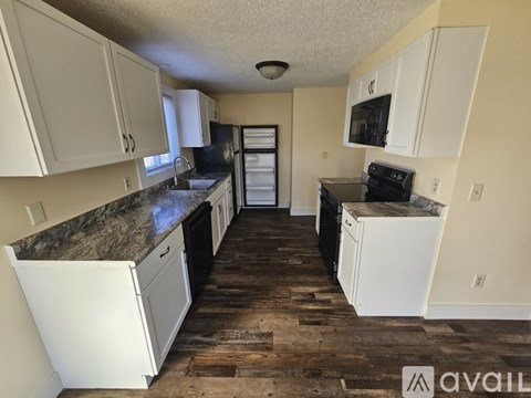 A kitchen with white cabinets and a granite countertop.
