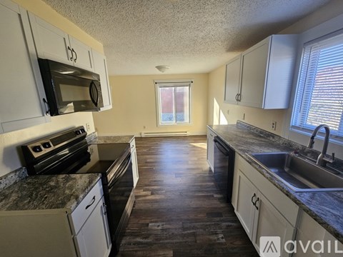 A kitchen with a black stove top oven and white cabinets.
