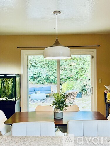 A living room with a white couch and a table with a plant on it.