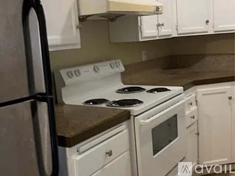 A kitchen with a white stove and white cabinets.