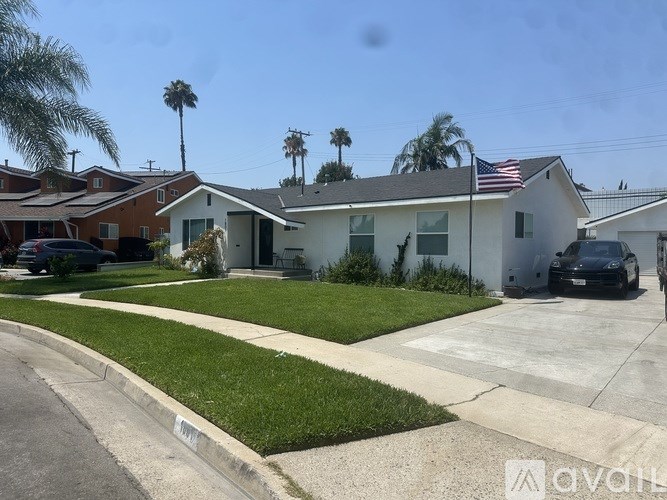 A house with a white front yard and a black car parked in front.