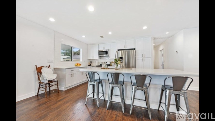 A kitchen with white cabinets and a wooden floor.