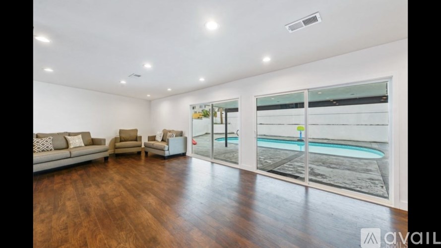A living room with a pool outside the window.