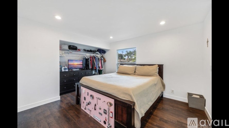 A bedroom with a bed, pillows, and a wall-mounted TV.