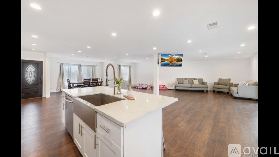 A modern kitchen with white cabinets and a wooden floor.