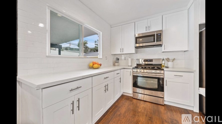A kitchen with white cabinets and a wooden floor.
