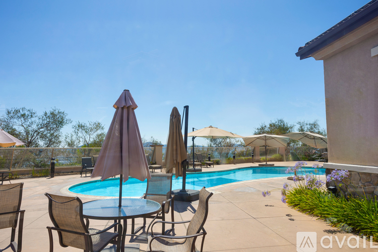 A poolside table with chairs and umbrellas overlooking a pool.