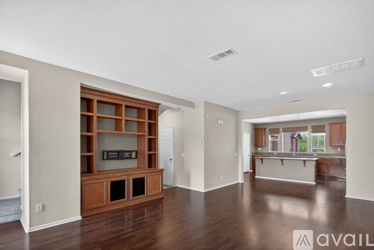 A spacious living room with a wooden entertainment center and a large window.