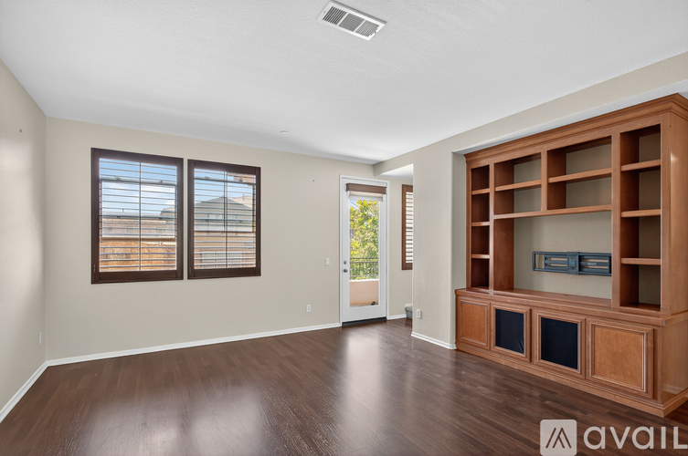 A spacious room with wooden floors and a large entertainment center.