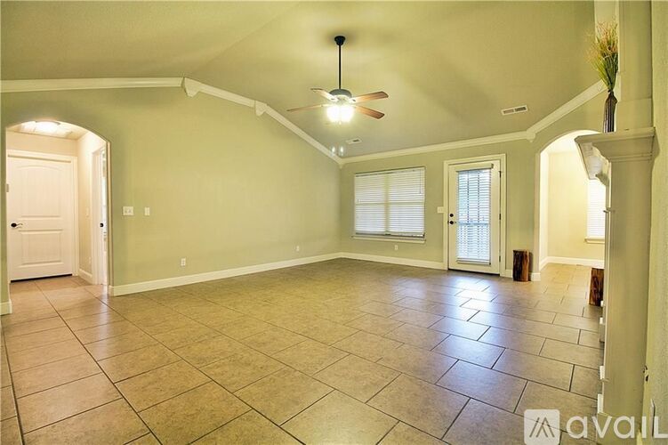 A spacious room with a fan and tile flooring.