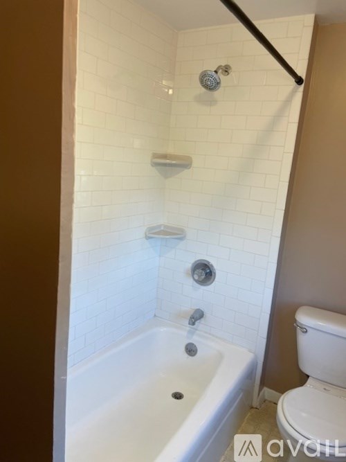 A white tiled bathroom with a white toilet and a white bathtub.
