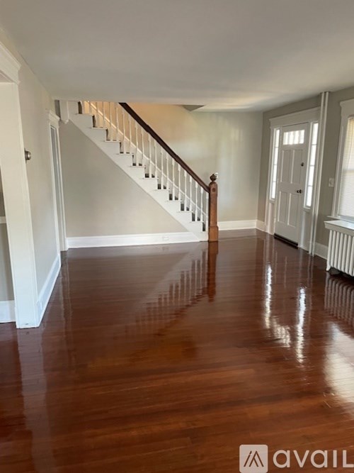 A spacious room with a wooden floor and a staircase.