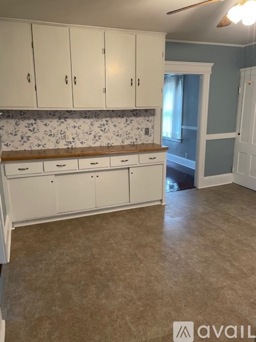 A kitchen with white cabinets and a countertop with a tile backsplash.