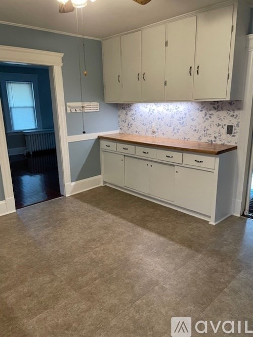 A kitchen with white cabinets and a wooden countertop.